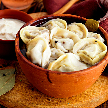 Пельмени по-деревенски с бульоном, сливочным маслом, сметаной и зеленью в горшочке